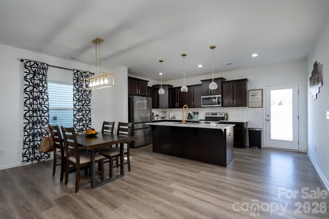 a kitchen with stainless steel appliances kitchen island granite countertop a dining table chairs and sink
