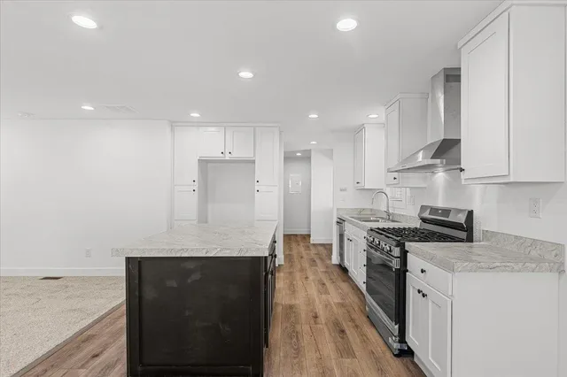 a large kitchen with stainless steel appliances granite countertop a stove a sink and a refrigerator