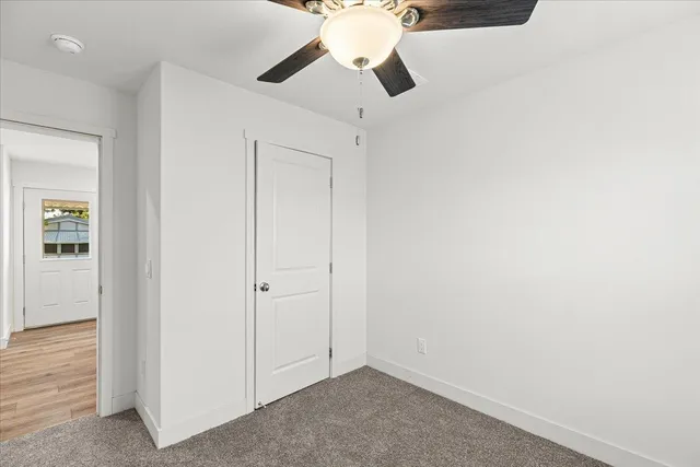 an empty room with closet and a chandelier fan