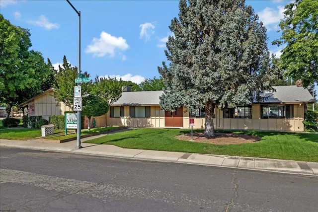 a view of a house with a yard and large trees
