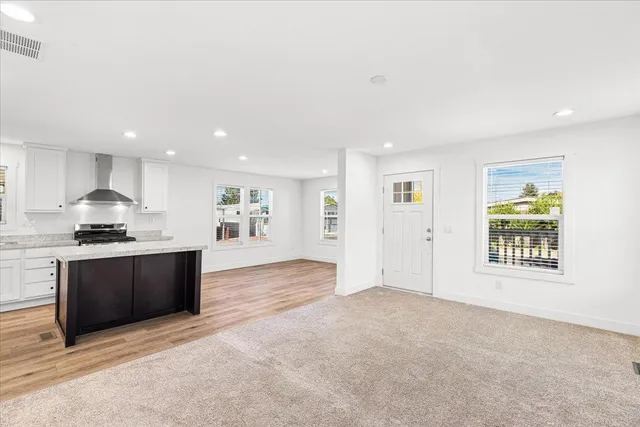 a view of kitchen with stainless steel appliances granite countertop a stove top oven a sink dishwasher and a refrigerator with wooden floor