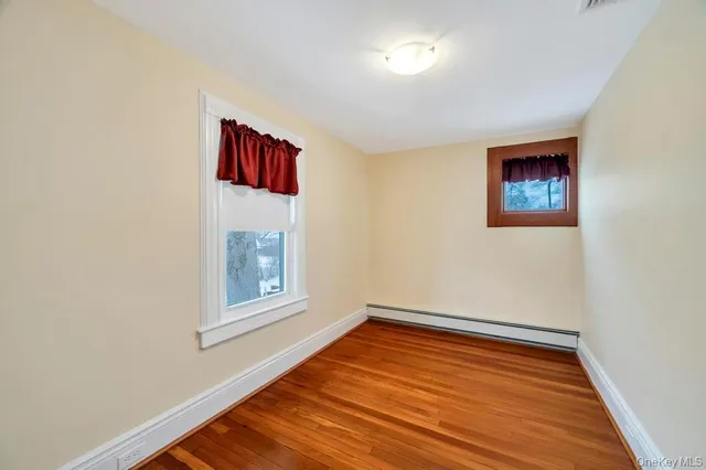 a view of an empty room with window and wooden floor