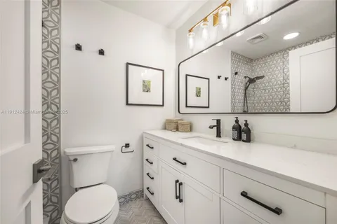 a bathroom with a granite countertop toilet sink and mirror