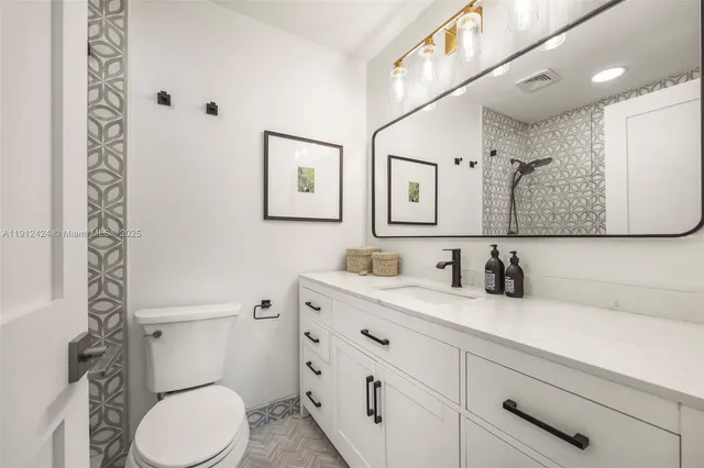a bathroom with a granite countertop toilet sink and mirror