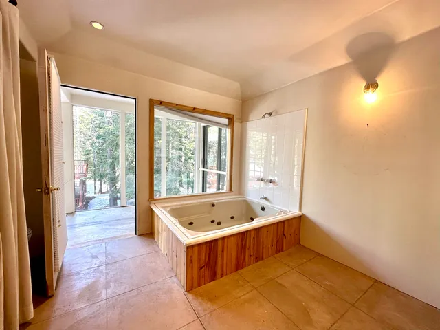 a bathroom with a tub a sink and a large window