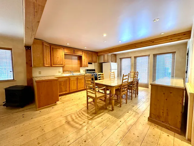 a kitchen with stainless steel appliances granite countertop a stove top oven a sink a dining table and chairs with wooden floor