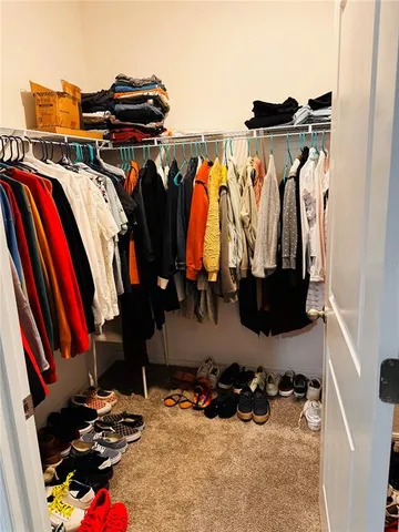 a view of walk in closet with clothes and shoes