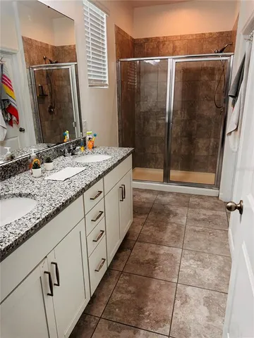 a bathroom with a granite countertop sink a mirror and shower