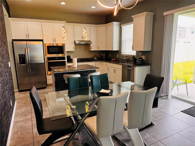 a kitchen with a table chairs refrigerator and microwave