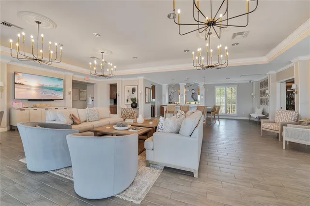 a living room with couches a chandelier and kitchen view