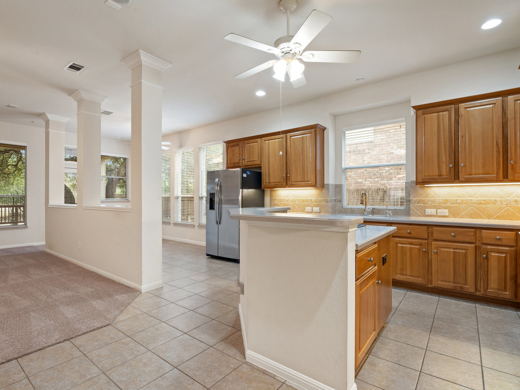 1858 Nelson Ranch Loop Cedar Park, TX 78613 - Photo 32 of 32 Kitchen featuring decorative backsplash, brown cabinets, stainless steel fridge with ice dispenser, a kitchen island, and open floor plan