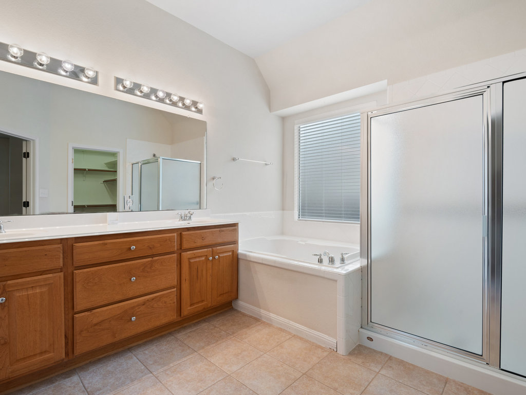 1858 Nelson Ranch Loop Cedar Park, TX 78613 - Photo 25 of 32 Full bathroom featuring a shower stall, double vanity, vaulted ceiling, a garden tub, and light tile patterned floors