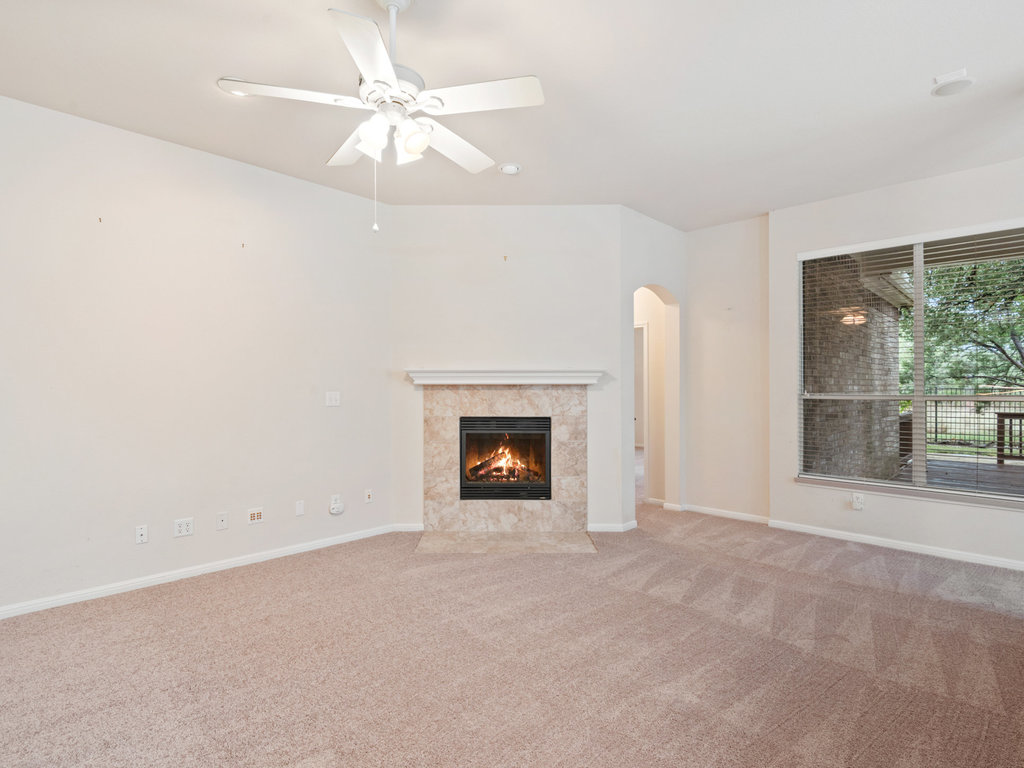 1858 Nelson Ranch Loop Cedar Park, TX 78613 - Photo 6 of 32 Unfurnished living room with a tiled fireplace, carpet flooring, ceiling fan, and arched walkways
