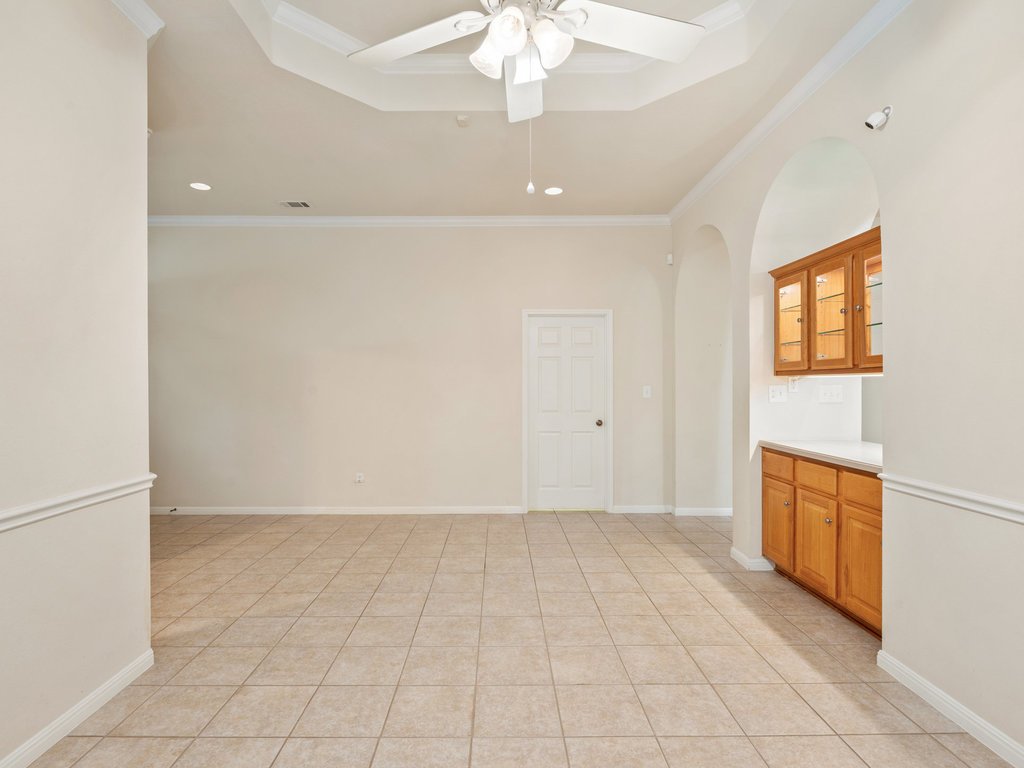 1858 Nelson Ranch Loop Cedar Park, TX 78613 - Photo 9 of 32 Spare room with light tile patterned flooring, arched walkways, crown molding, a ceiling fan, and a tray ceiling
