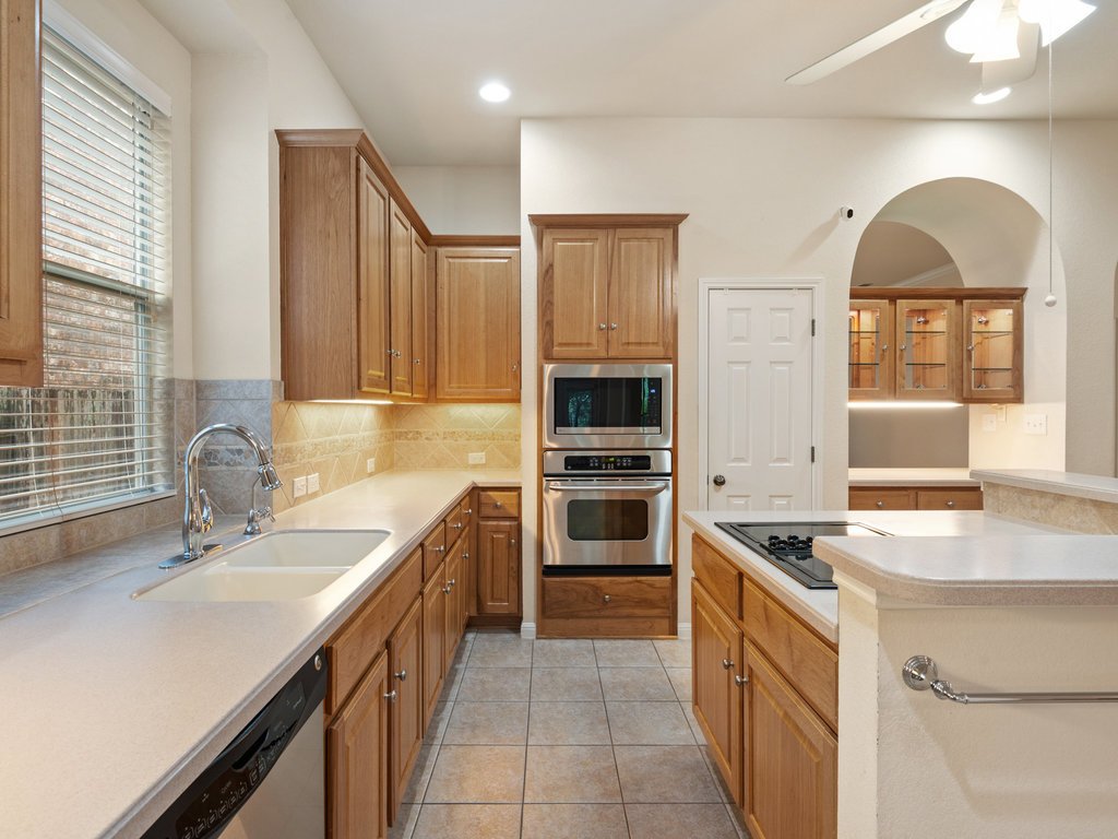 1858 Nelson Ranch Loop Cedar Park, TX 78613 - Photo 10 of 32 Kitchen with stainless steel appliances, light tile patterned flooring, a ceiling fan, brown cabinets, and decorative backsplash