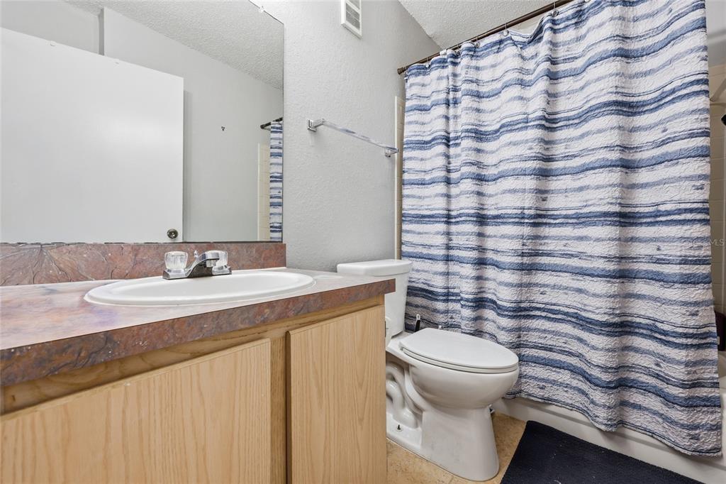 3705 Southwest 27th Street, Unit 717 Gainesville, FL 32608 - Photo 12 of 24 a bathroom with a granite countertop sink a toilet and a mirror