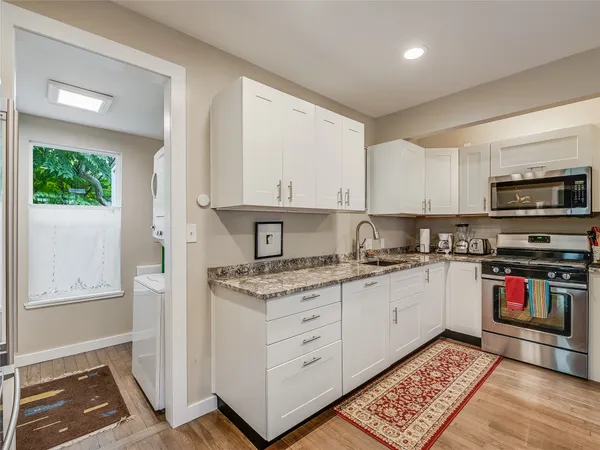 a kitchen with stainless steel appliances granite countertop a stove a sink and a microwave