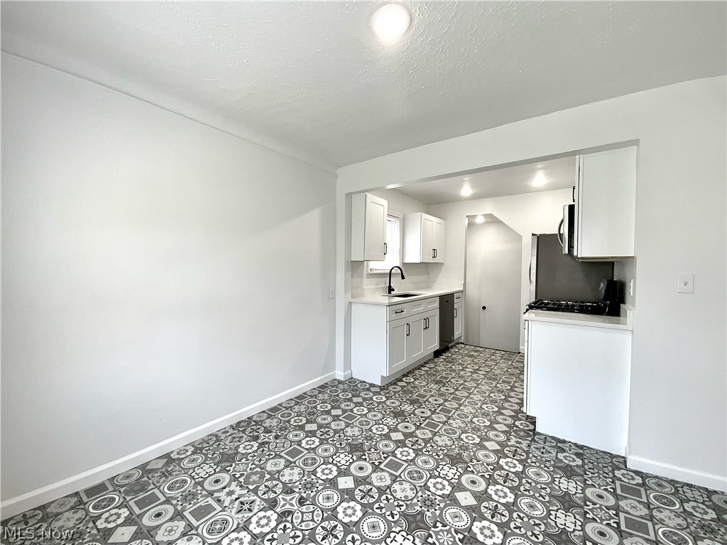 1844 Oakmount Road Cleveland, OH 44121 - Photo 8 of 26 Kitchen with a textured ceiling, sink, white cabinetry, dishwashing machine, and tile floors