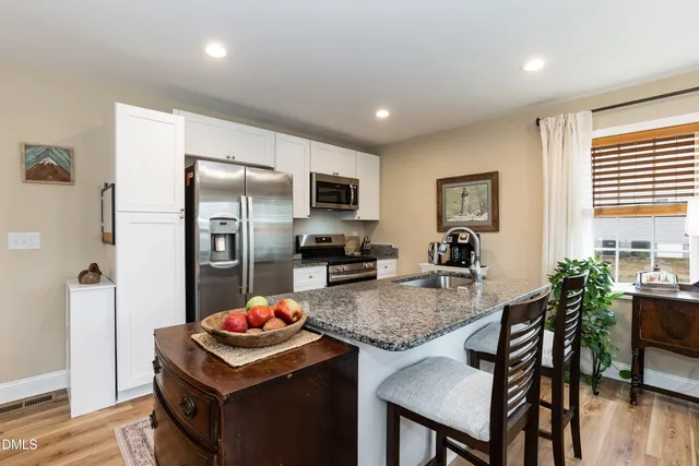 a kitchen with granite countertop kitchen island stainless steel appliances a sink stove and refrigerator