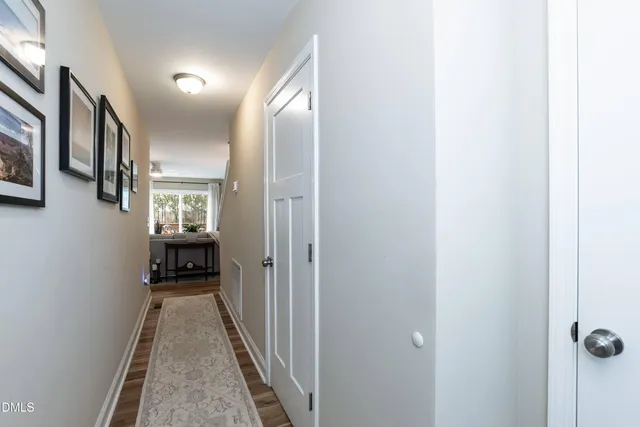 a view of a hallway with wooden floor and a bathroom