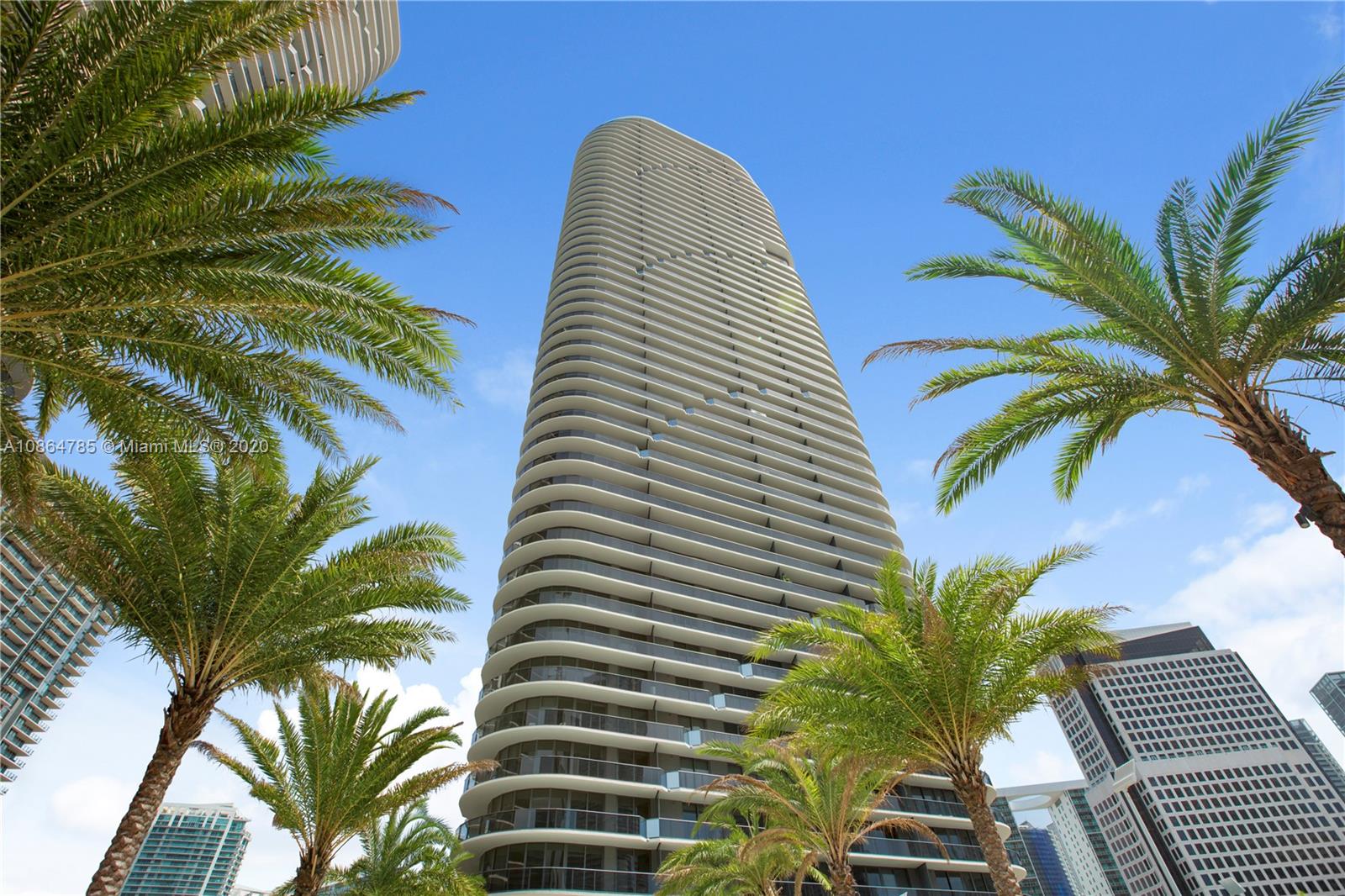 a view of a tall white building with a palm tree in the background