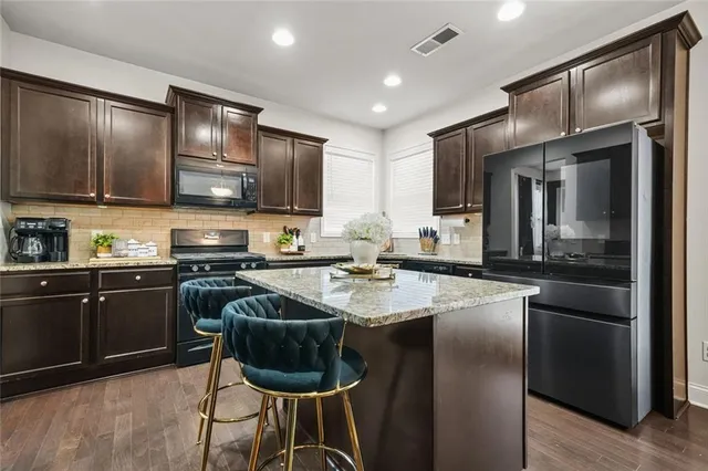 a view of kitchen with stainless steel appliances granite countertop dining table chairs cabinets and wooden floor