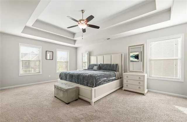 a bedroom with a large bed and a chandelier fan