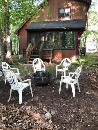 a view of a wooden chairs and table in backyard of the house
