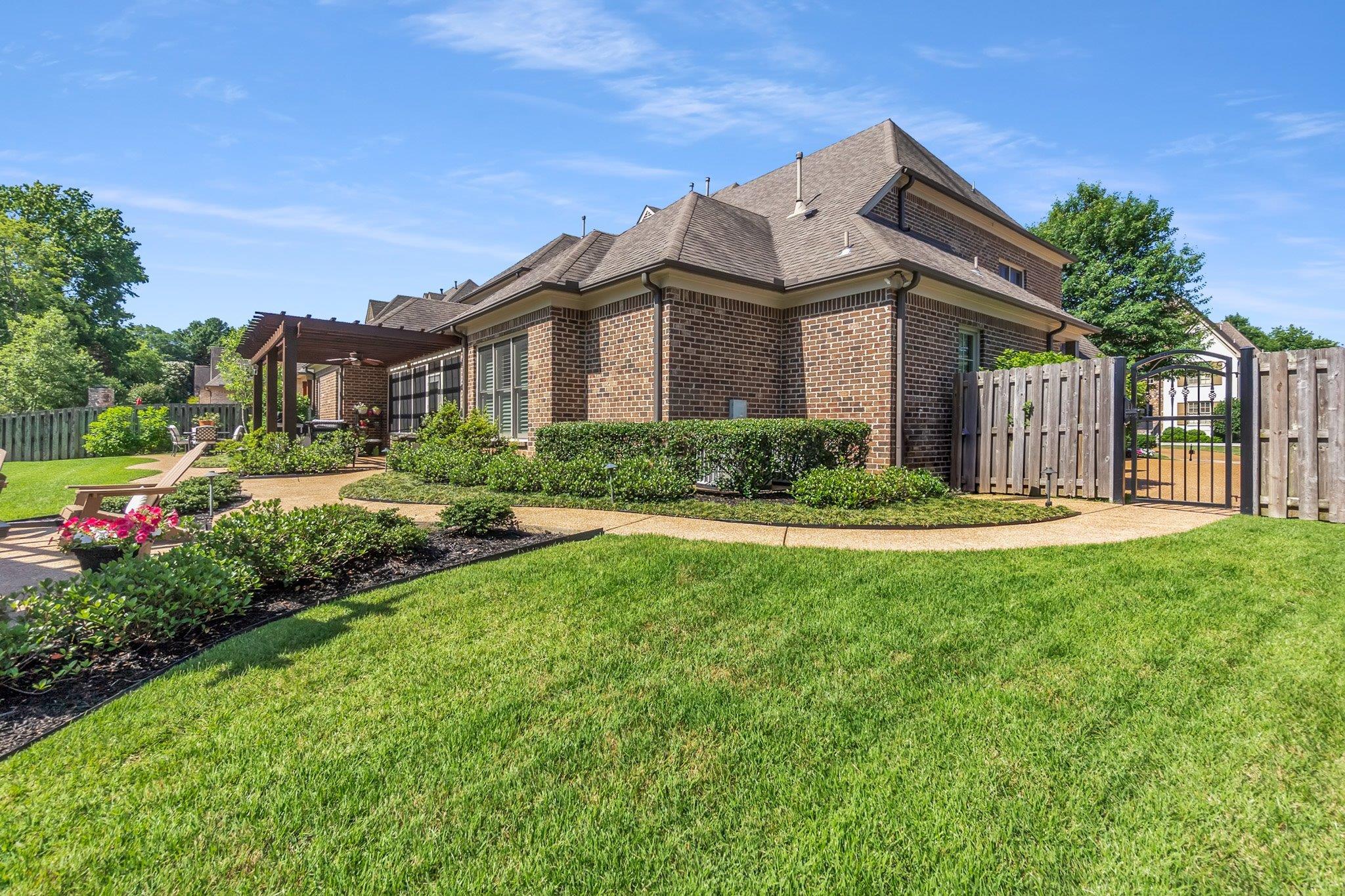3246 North Hartwell Ridge Drive Collierville, TN 38017 - Photo 38 of 40 Expansive rear yard featuring a brick exterior, a pergola-covered patio, mature landscaping, and a gated perimeter fence