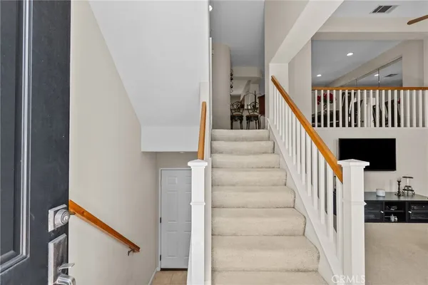 a view of staircase with lots of frames on wall and a dining table