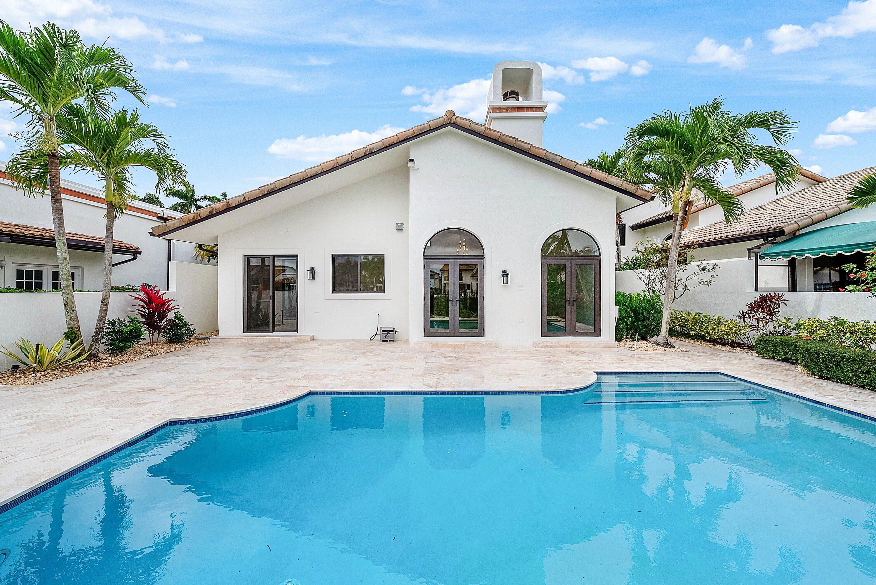 6547 Via Rosa Boca Raton, FL 33433 - Photo 45 of 55 a view of a white house with a swimming pool and a lawn chairs under an umbrella