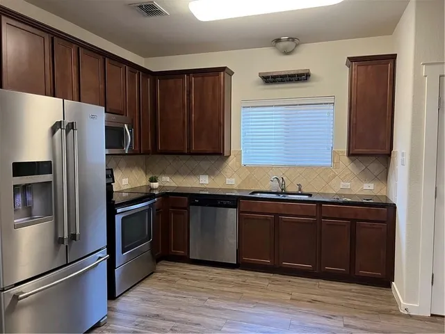 a kitchen with stainless steel appliances granite countertop a refrigerator and a sink