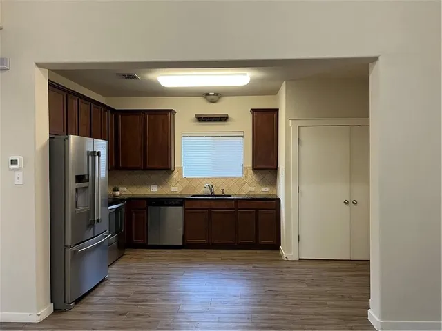 a large kitchen with granite countertop a refrigerator and a stove top oven