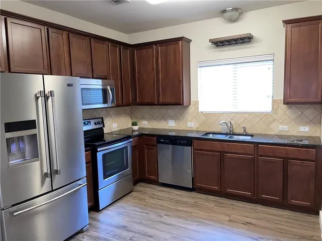 a kitchen with granite countertop wooden cabinets a refrigerator and a sink