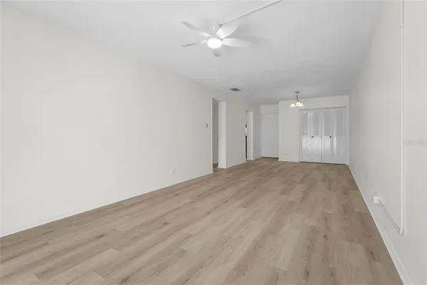 an empty room with wooden floor and fan