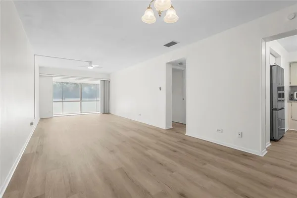 a view of empty room with wooden floor and fan