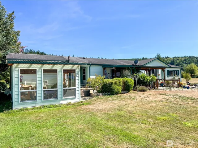 a view of a house with potted plants and a large tree