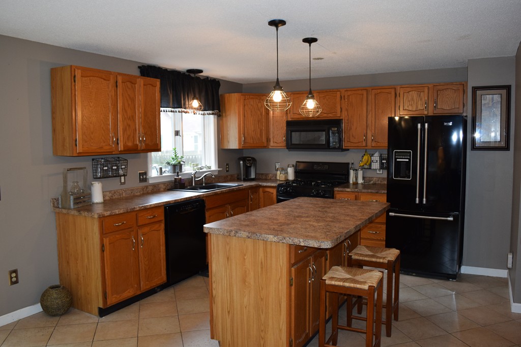 54 Luden Street Springfield, MA 01118 - Photo 3 of 24 a kitchen with a refrigerator a sink a counter space and cabinets
