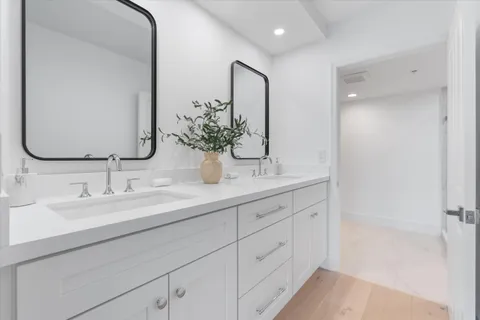 a bathroom with double vanity and a mirror