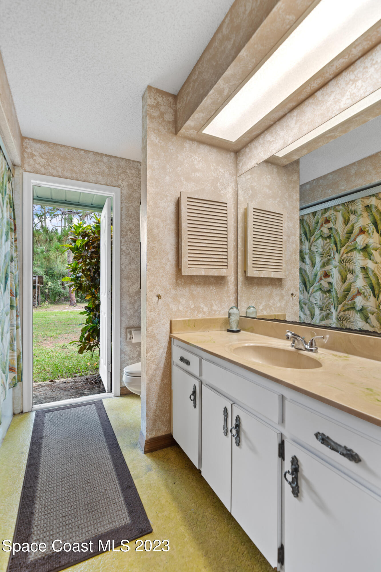 3836 Hield Road Northwest Palm Bay, FL 32907 - Photo 29 of 55 a spacious bathroom with a granite countertop sink and a large mirror next to a window