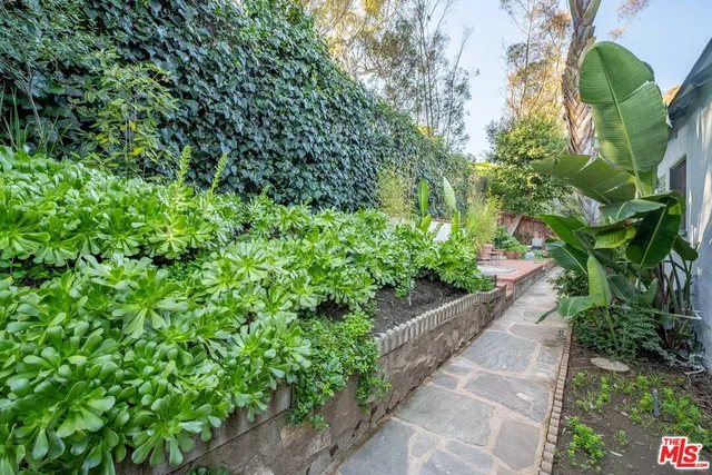 a front view of a house with a garden and trees