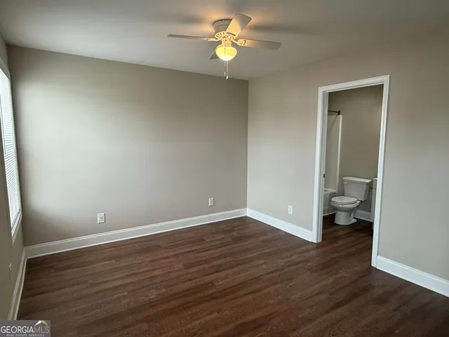 an empty room with wooden floor and a ceiling fan