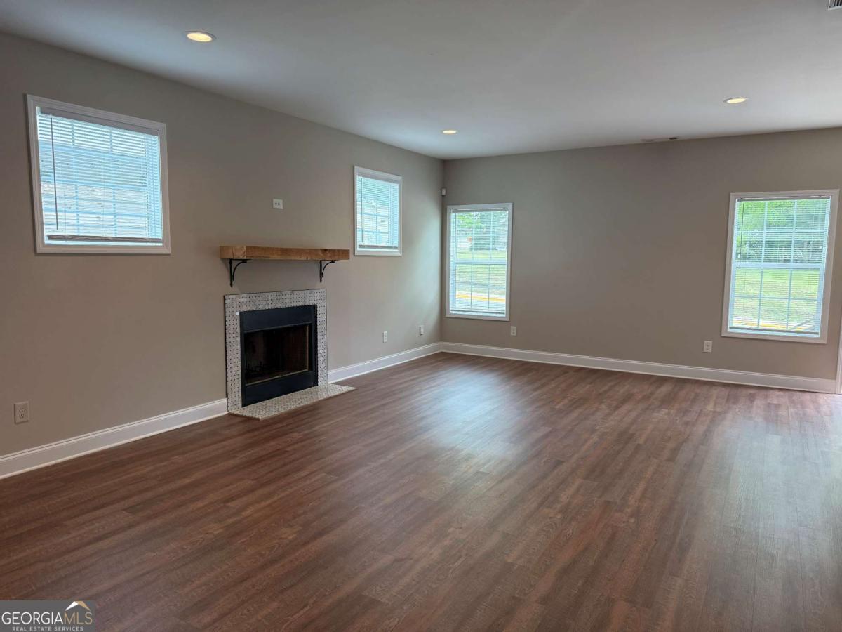 790 Grove Street Gainesville, GA 30501 - Photo 5 of 15 an empty room with wooden floor a fireplace and windows