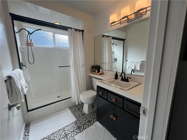 a bathroom with a sink a toilet a mirror and shower