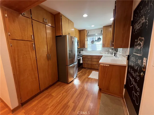 a kitchen with refrigerator a sink a stove and wooden floor