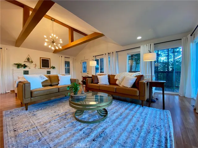 a living room with furniture a chandelier and a dining table with wooden floor
