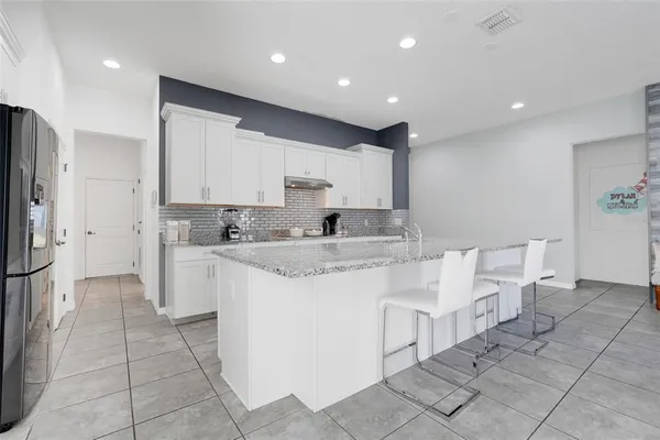 a large white kitchen with stainless steel appliances kitchen island granite countertop a sink and cabinets