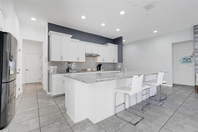 a large white kitchen with stainless steel appliances kitchen island granite countertop a sink and cabinets