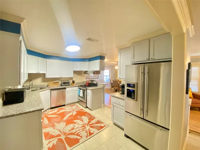 a kitchen with a refrigerator a stove top oven and white cabinets