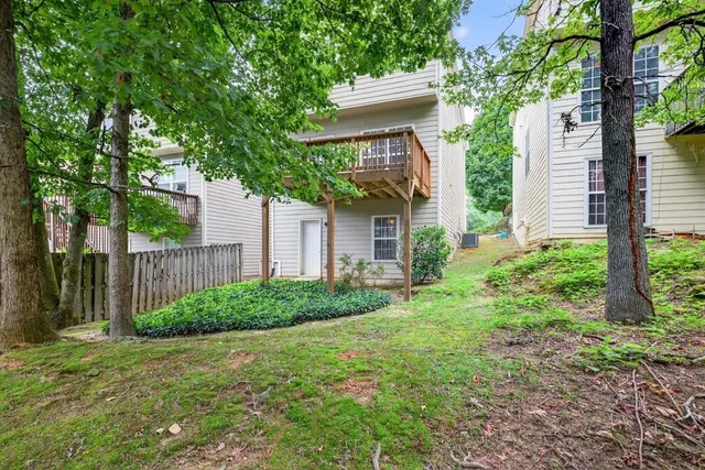 a view of a yard with plants and large trees